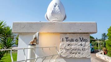 Een wit stenen monument met een bladachtige bovenkant en een plaquette met de tekst 'I Trulli di Vito, San Cataldo, 67, Zona M'.