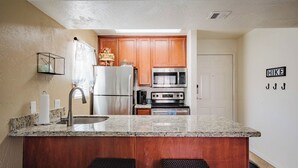 A modern kitchen with wooden cabinets, stainless steel appliances, and a granite countertop. - Adventure Loft: Near Trails, Pool and Golf (Sedona)