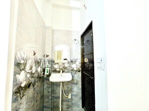 A bathroom with a white sink, a mirror, and a shower area. - Majestic Guest House (Varanasi)