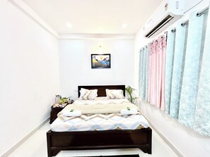 Quarto com cama, mesa de cabeceira e ar condicionado fixado na parede.
