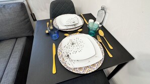 Una mesa para comer dispuesta con platos, cubiertos y vasos, con un camino de mesa estampado.