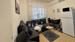 Un espacio habitable compacto con sofá, mesa de comedor y kitchenette.
