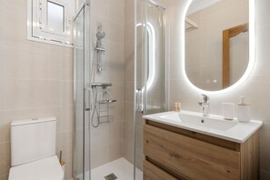 A modern bathroom with a glass-enclosed shower, a white sink with wooden vanity, and a large mirror. - Marvelous Waterfront apt in Fuengirola - Ref 73 (Fuengirola)