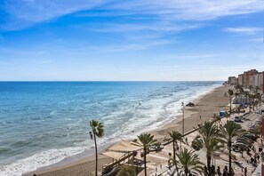 A beach with a sandy shore, palm trees, and a promenade with buildings and parked cars. - Marvelous Waterfront apt in Fuengirola - Ref 73 (Fuengirola)