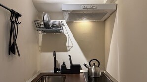 Una cucina compatta con un lavello a due scomparti, un bollitore e uno scolapiatti.