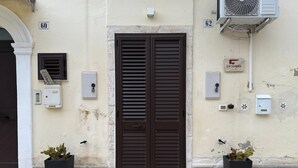 Facciata di un edificio con un'entrata a doppia porta, numeri civici e armadietti utenze.