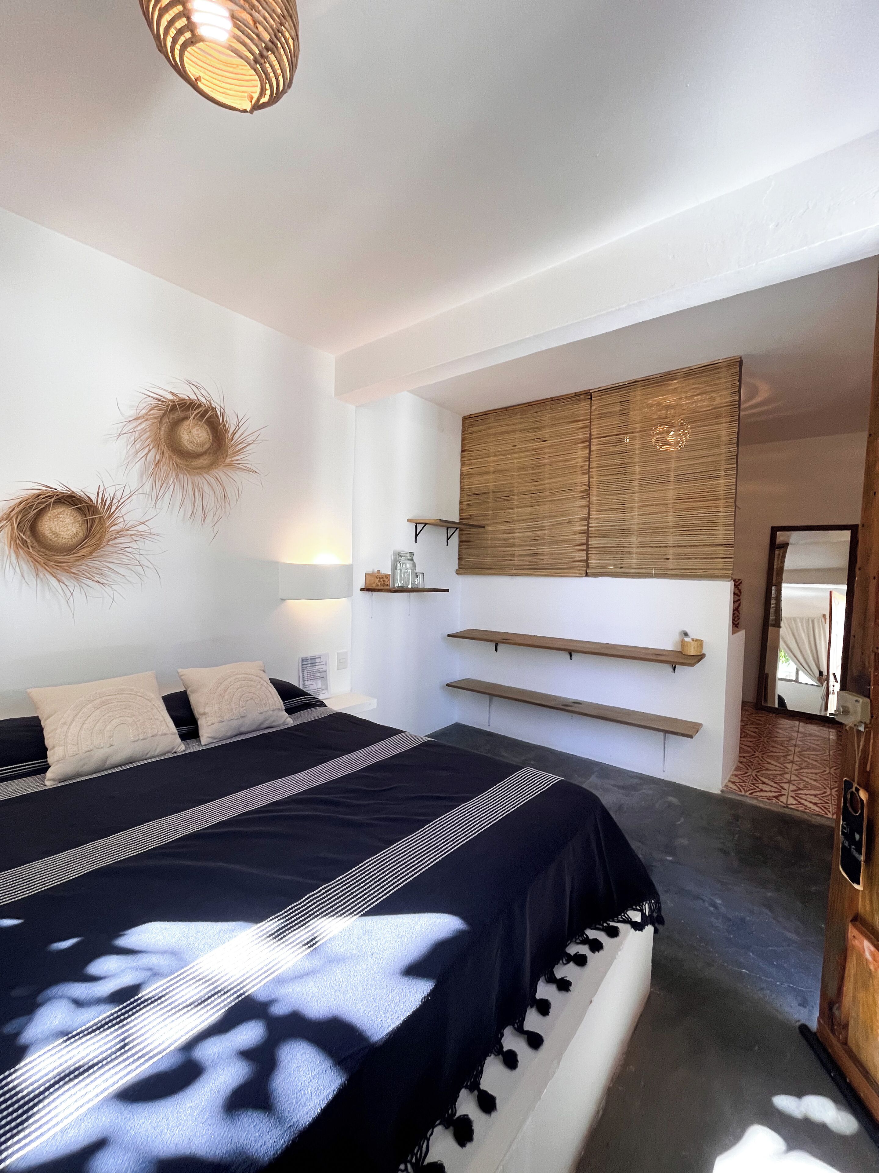 Un dormitorio moderno con una cama grande, mesitas de noche, una lámpara colgante y un estante en la pared.