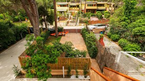 Un cortile con recinzione in legno, un piccolo giardino e un edificio con diversi balconi.