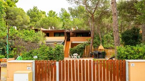 Un edificio residenziale con recinzione in legno, un piccolo patio con mobili da esterno e una scala che conduce a un secondo piano.