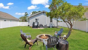 Un jardin avec un foyer extérieur, du mobilier de jardin et une maison en arrière-plan.