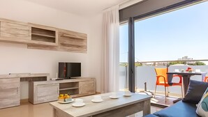 A modern living room with a flat-screen TV, a wooden coffee table, and a sofa. - Apartment 'Tropikana I' with Shared Pool, Wi-Fi and Air Conditioning (Miami Platja)