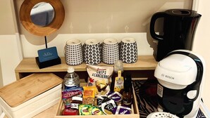 Keittiön työtasolla on kahvinkeitin, vedenkeitin ja laatikko, jossa on pientä purtavaa.