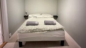 Un dormitorio con una cama, dos mesitas de noche y una puerta.