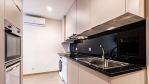 Een moderne keuken met een roestvrijstalen spoelbak, een inbouwoven en een vaatwasser.