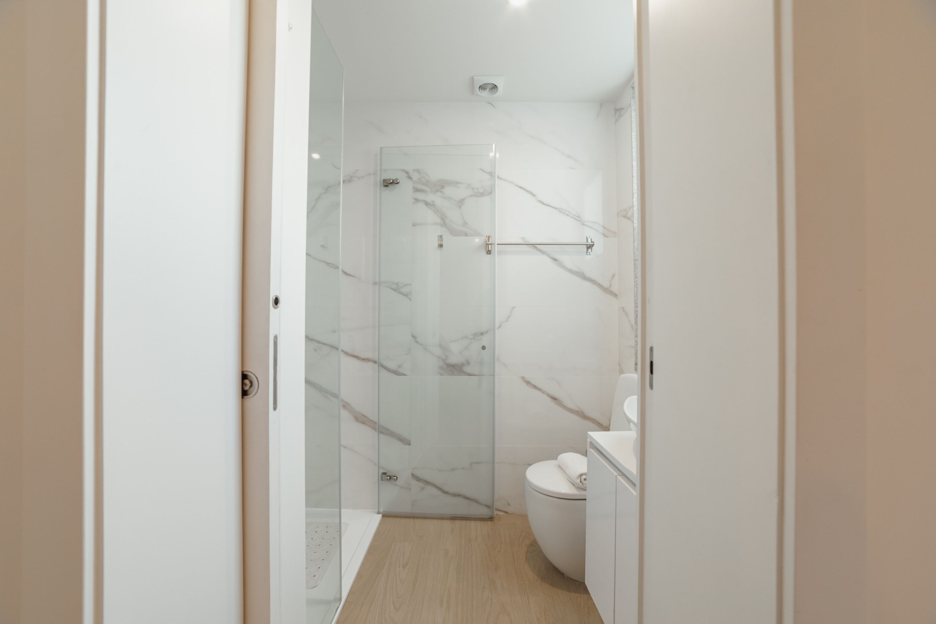 Un baño moderno con cabina de ducha de vidrio, inodoro y lavamanos.