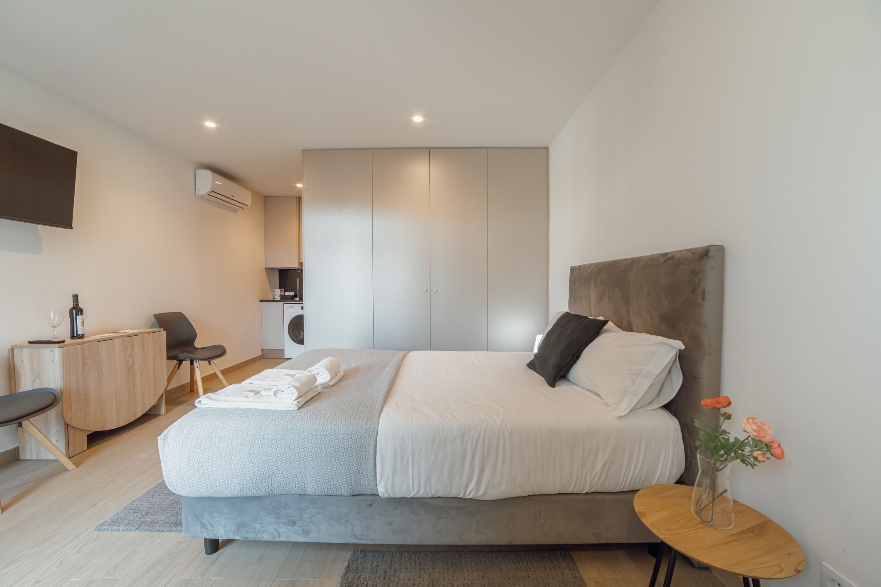 Un dormitorio moderno con cama, mesita de noche y un pequeño escritorio.