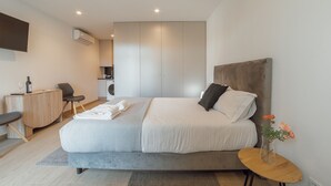 Een moderne slaapkamer met een bed, nachtkastje en een klein bureau.