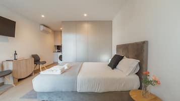 Un dormitorio moderno con cama, mesita de noche y un pequeño escritorio.
