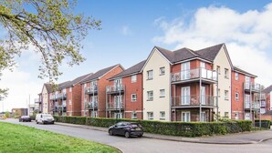 Un immeuble résidentiel à plusieurs étages, doté de balcons et d’une allée pavée.