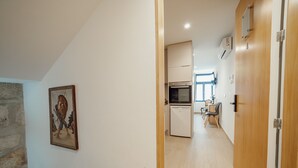 A hallway leading to a kitchen with a dishwasher, a dining area with a table and chairs, and a wooden door. - Carmo Residence Porto - S ANA by Vacationy (Porto)