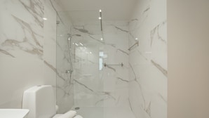 A modern bathroom with a glass-enclosed shower, a white toilet, and a marble wall. - Carmo Residence Porto - S ANA by Vacationy (Porto)