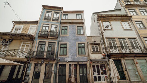 A row of multi-story buildings with balconies, a shop with a sign reading "Casa de Cario", and a closed shop with a sign that reads "Bread & Best". - Carmo Residence Porto - S Luis by Vacationy (Porto)