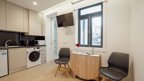 A modern kitchen with appliances, a washing machine, and a dining area with two chairs and a table. - Carmo Residence Porto - S Luis by Vacationy (Porto)