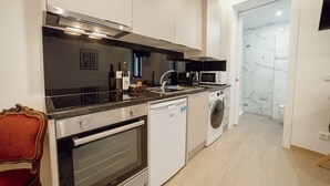 A modern kitchen with a dishwasher, oven, microwave, and a red chair. - Carmo Residence Porto - S Luis by Vacationy (Porto)