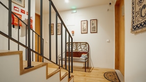 A staircase with wooden steps and black metal railings, leading to a landing with a bench and framed pictures on the wall. - Carmo Residence Porto - S Helena by Vacationy (Porto)