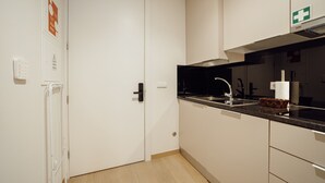 A modern kitchen with a black countertop, stainless steel sink, and a white door. - Carmo Residence Porto - S Helena by Vacationy (Porto)