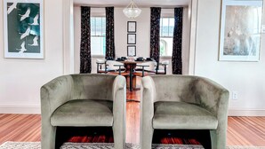 Un coin repas comprenant une table ronde, deux fauteuils et un lustre.