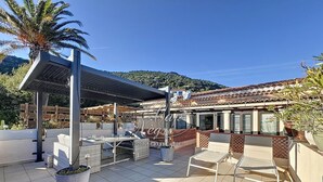 Une terrasse sur le toit, aménagée avec du mobilier d’extérieur, une pergola et offrant une vue sur une montagne.