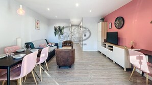 Un salon moderne avec un coin repas, comprenant un canapé, des fauteuils, une table basse et un téléviseur.