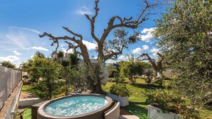 Un jacuzzi rodeado de follaje y un árbol.