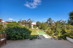 A backyard with a lawn, two lounge chairs, a small pool, and surrounding greenery.