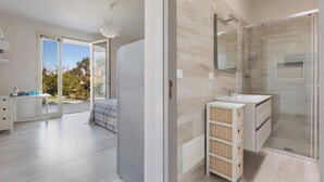 Un baño moderno con cabina de ducha de vidrio, lavamanos y cestos de mimbre.