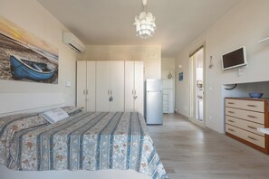 A bedroom with a bed, wardrobe, and a television on a stand.