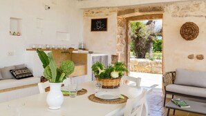 Un comedor acogedor con una mesa blanca, una cesta de verduras frescas y vistas al exterior.