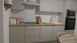 Une cuisine moderne équipée d’un four encastré, d’un micro-ondes, d’un évier et d’un coin repas avec une table ronde et des chaises.