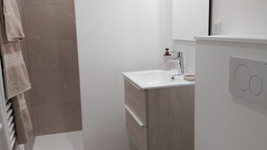 Une salle de bain moderne avec un lavabo blanc, un meuble-lavabo en bois et des toilettes blanches.