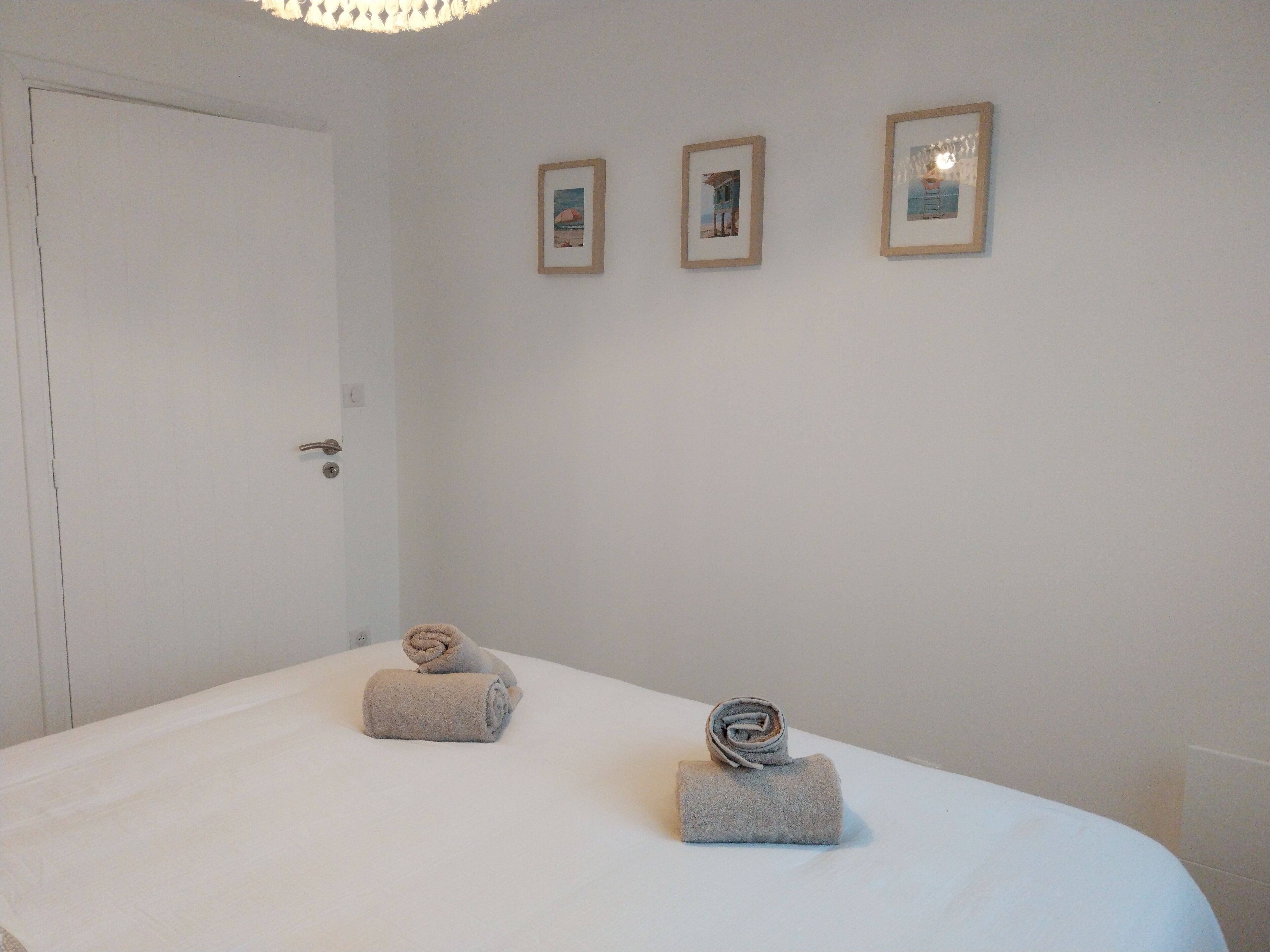 Ein Hotelzimmer mit einem Bett, zwei Handtüchern und drei gerahmten Bildern an der Wand.