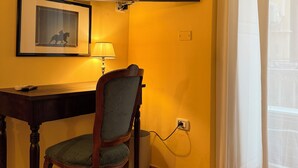 A room with a desk, chair, air conditioning unit, television, and a window with curtains. - Palazzo Dogana Room & Suite (Salerno)