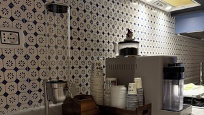 A kitchen with patterned tiles, a coffee machine, a kettle, and a wooden box with cookies. - Palazzo Dogana Room & Suite (Salerno)