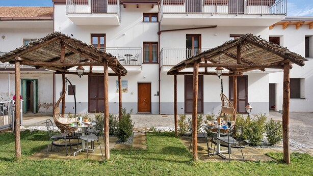 Een gebouw met twee verdiepingen, een binnentuin, terras en een houten pergola.