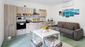 Een moderne keuken met een eettafel, een bank en een wandairconditioning.