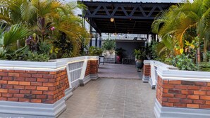 A covered walkway with brick walls and potted plants. - Heritage Hotel (Winneba)