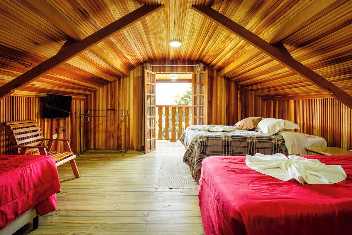 Acogedora habitación de cabaña de madera con dos camas, una silla de madera y un balcón con vistas.