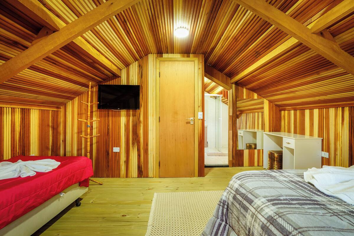 Un interior de madera con dos camas, un televisor y un armario blanco.