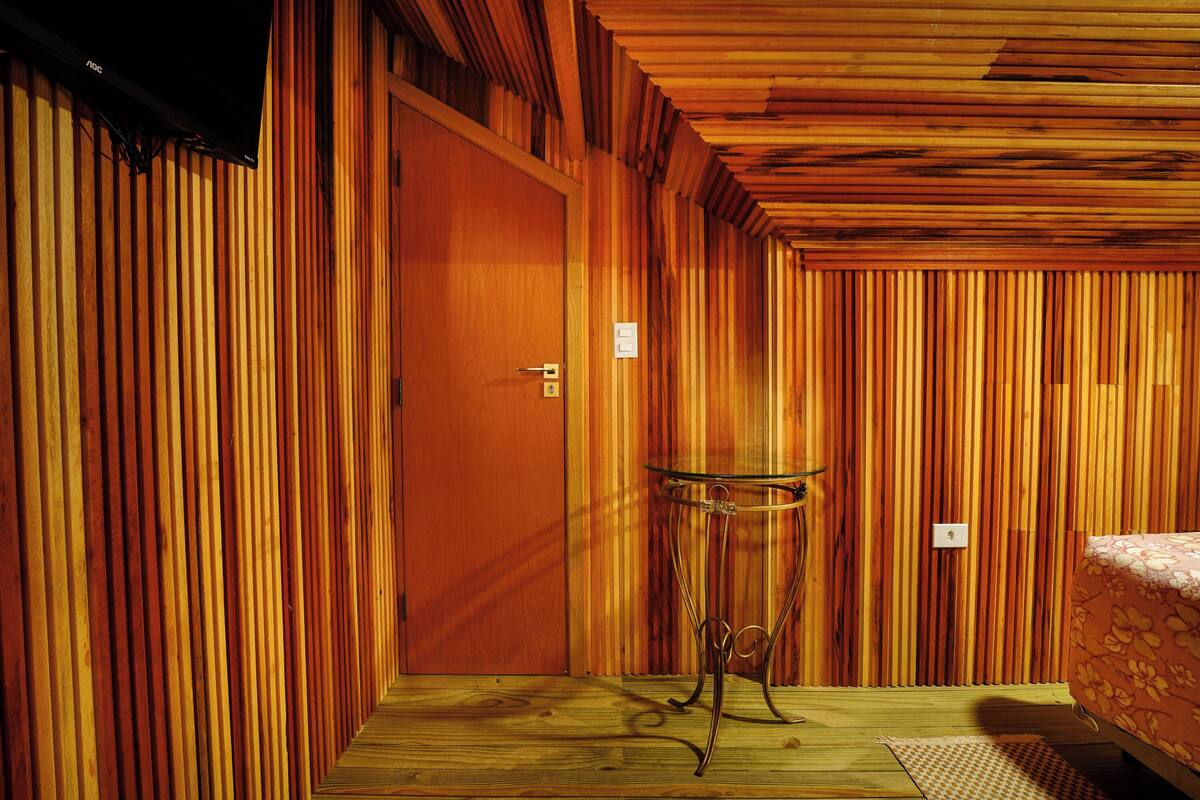 Una habitación con paneles de madera, una cama y una pequeña mesa.