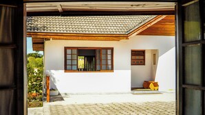 A traditional house with a tiled roof, a wooden door, and a window with wooden shutters. - VELINN Pousada Villa Paty II (Campos do Jordão)